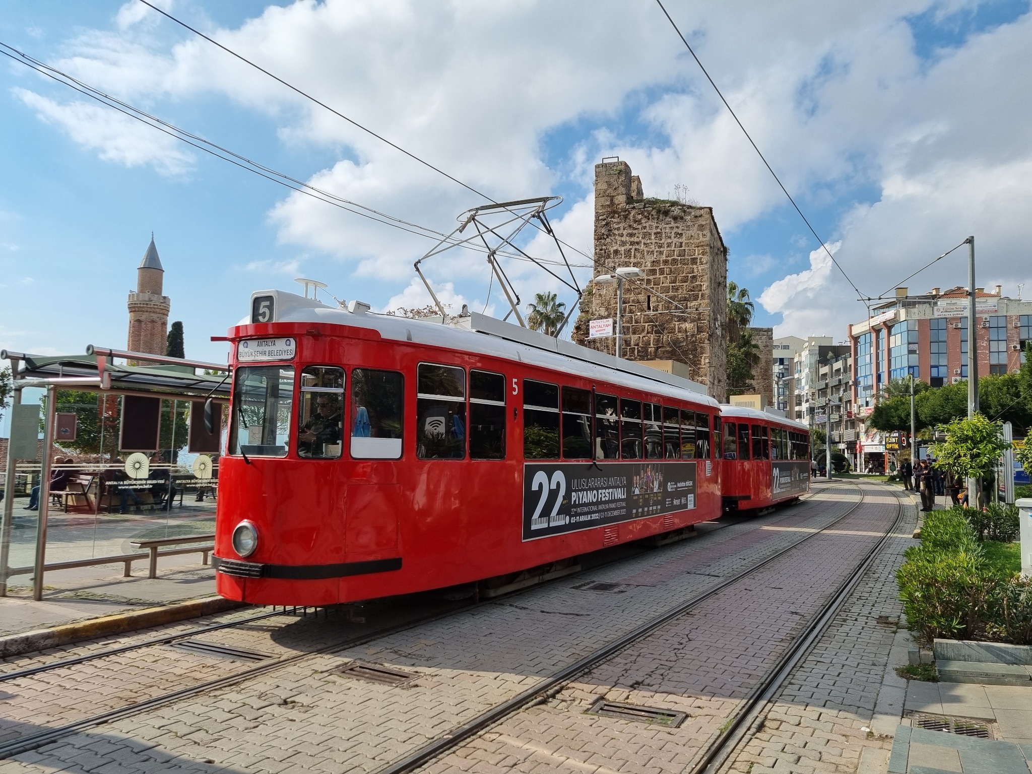 Historic red tram passing Antalya old town walls in the city center