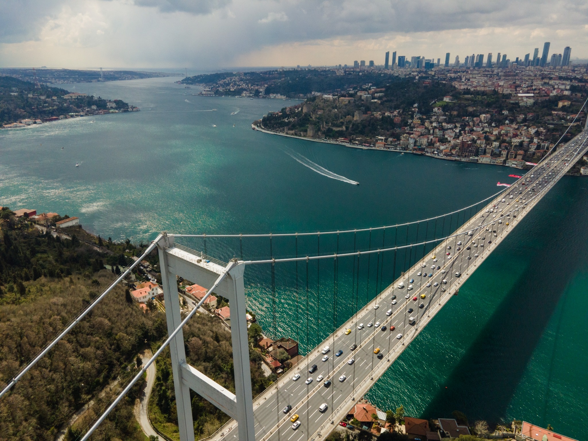 Aerial view of the Bosphorus Bridge crossing the strait between Istanbul's European and Asian shores. A high aerial view of the Bosphorus Bridge, officially the 15 July Martyrs Bridge, carrying traffic across the Bosphorus between the two sides of Istanbul, with boats, waterfront neighborhoods, and the city skyline beyond.