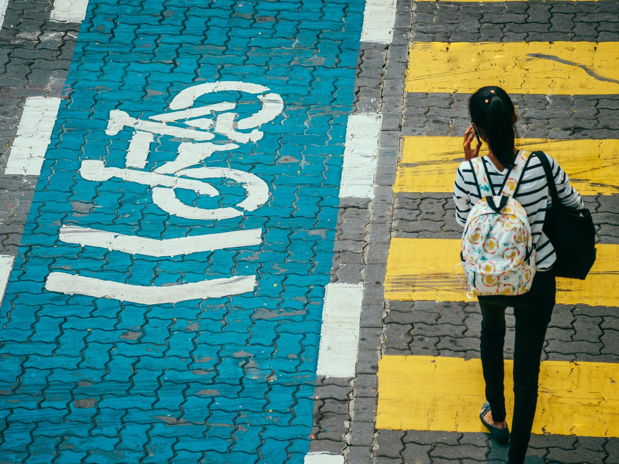 A pedestrian walks beside a brightly painted bicycle lane and yellow crossing in Kuala Lumpur.