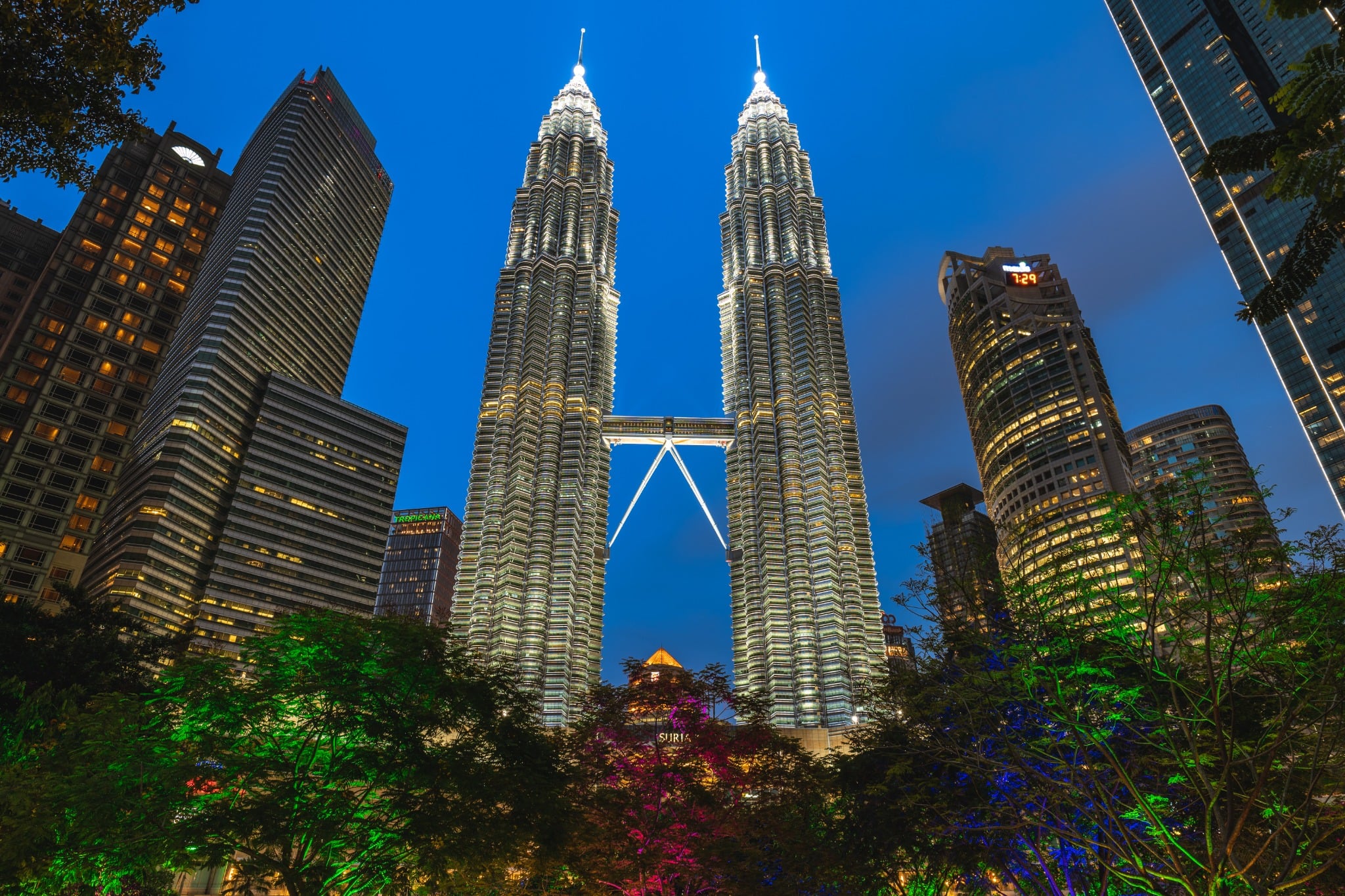 The Petronas Twin Towers glow above the surrounding skyscrapers in central Kuala Lumpur at night.