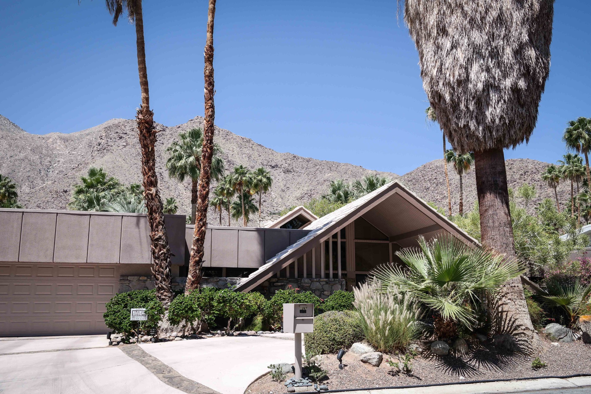Mid-century modern home with an A-frame roof, palm trees and mountains in Palm Springs