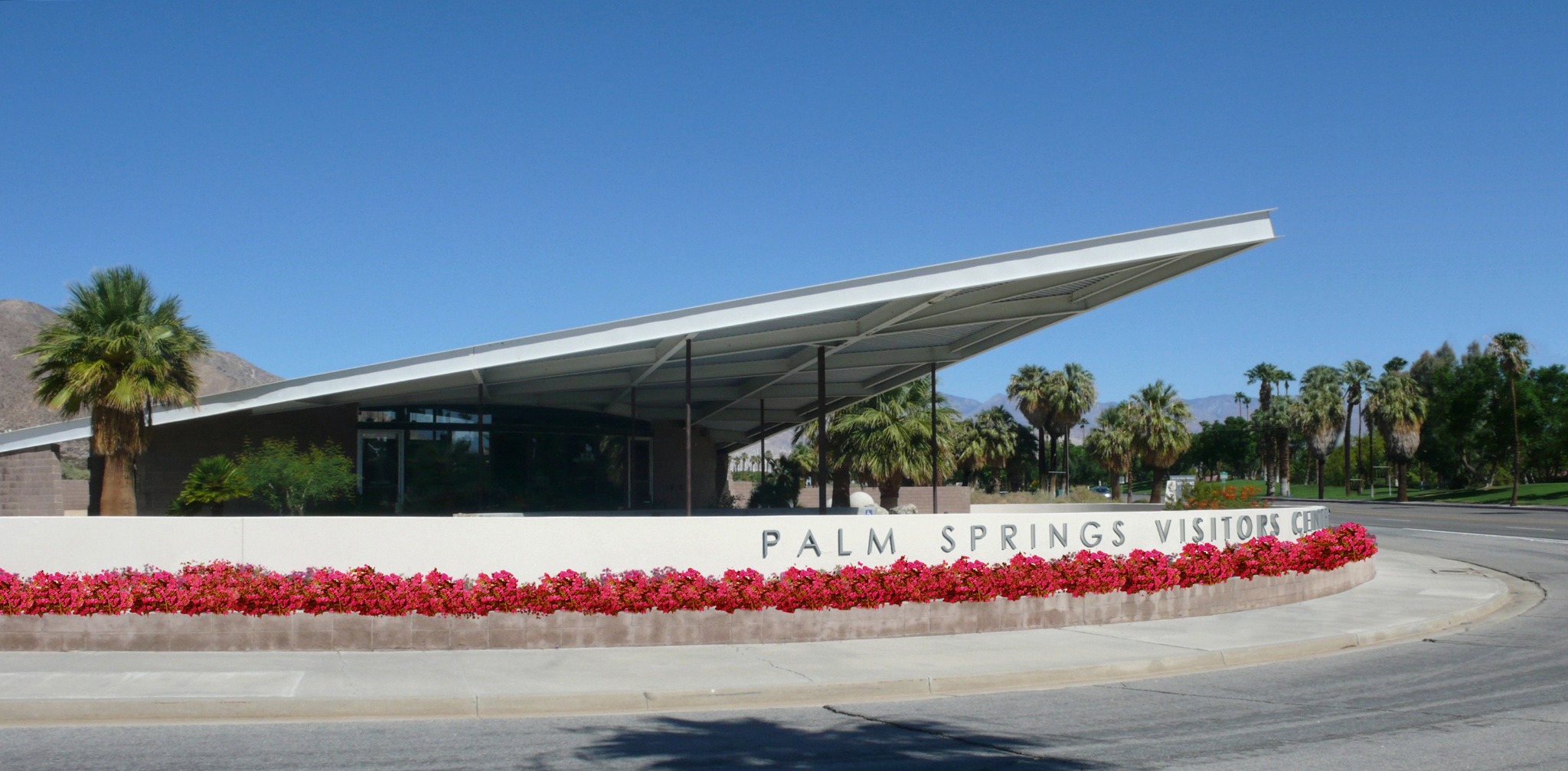 Palm Springs Visitor Center with modern roof, palm trees and desert mountains