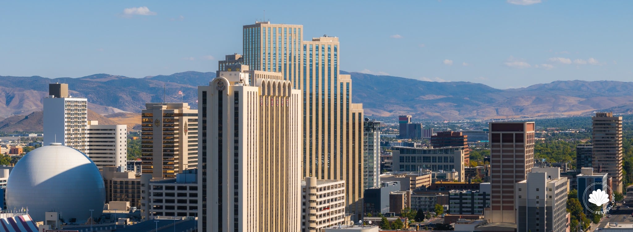 Aerial panorama of downtown Reno featuring the National Bowling Stadium and surrounding mountains.