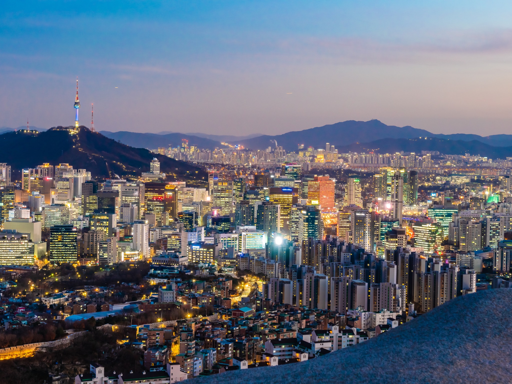 Seoul city skyline glowing at dusk with N Seoul Tower on Namsan Mountain.