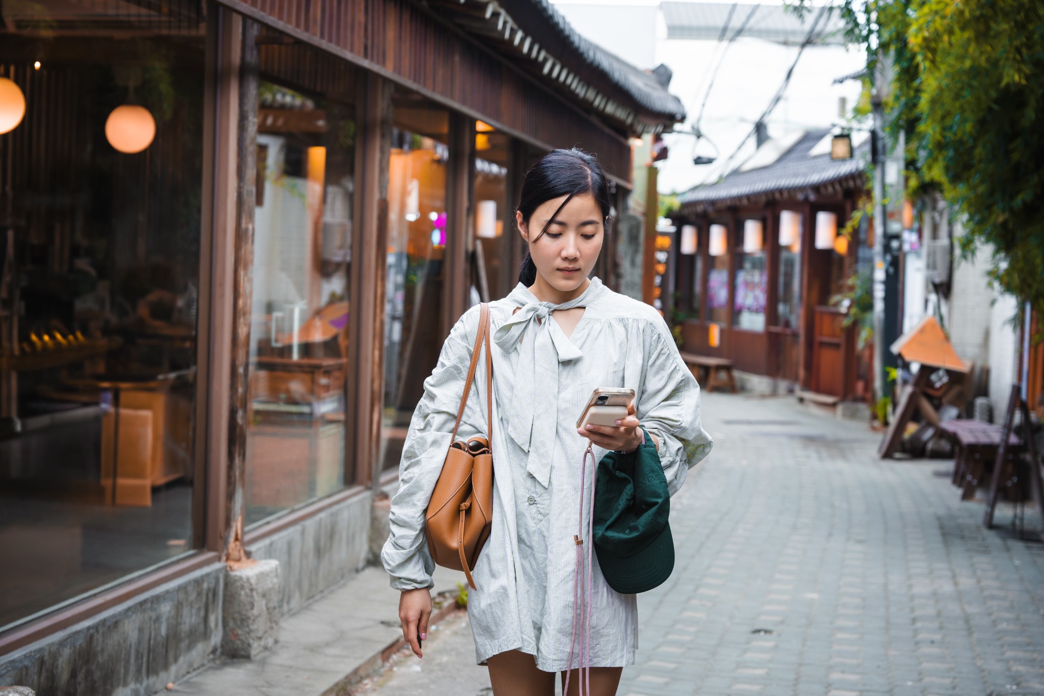 Female tourist using a smartphone while walking along a traditional street in Seoul, South Korea.