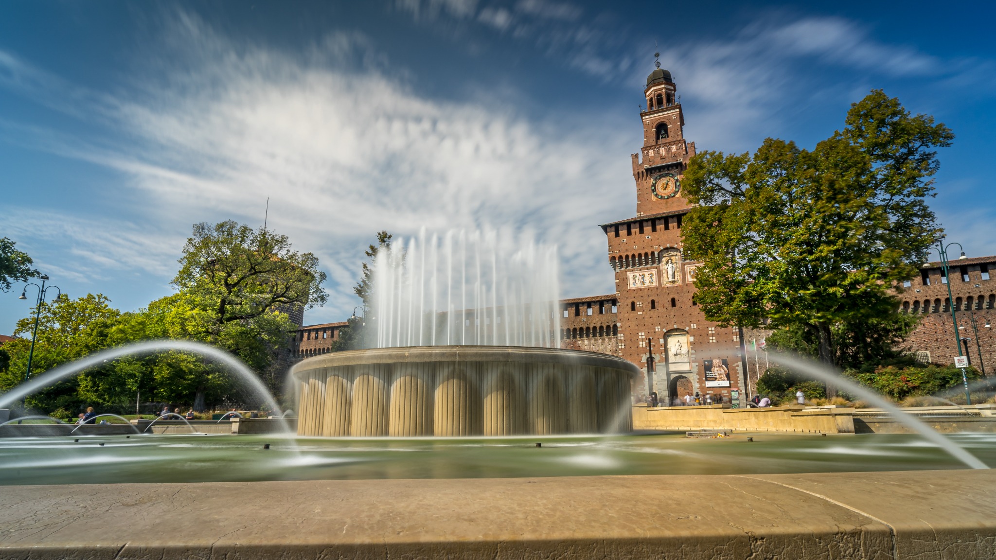 Scenic daytime view of the fountain and the Torre del Filarete entrance of Sforza Castle, a major historic attraction in central Milan.
