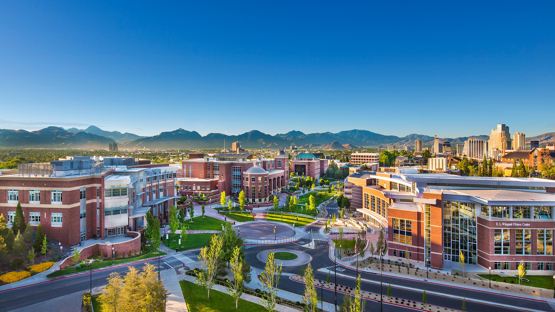 University of Nevada, Reno campus with brick academic buildings and mountains in the background.